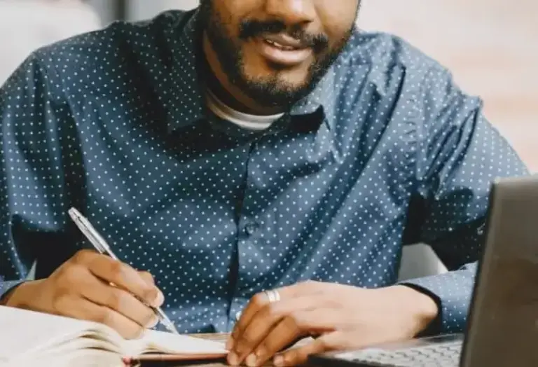 Optimized-african-american-man-working-laptop-writing-notebook-ezgif.com-jpg-to-webp-converter